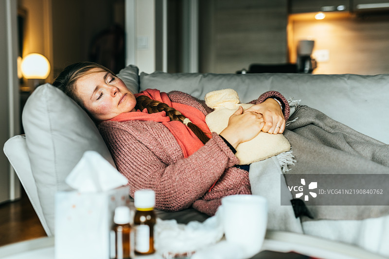 女人躺在沙发上，感冒并感到不适。图片素材