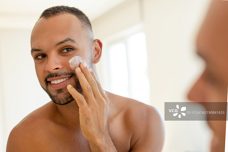 帅气的男人涂抹保湿霜图片素材