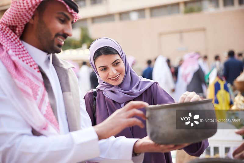 夫妻俩在跳蚤市场专注地看着一个古董罐子图片素材
