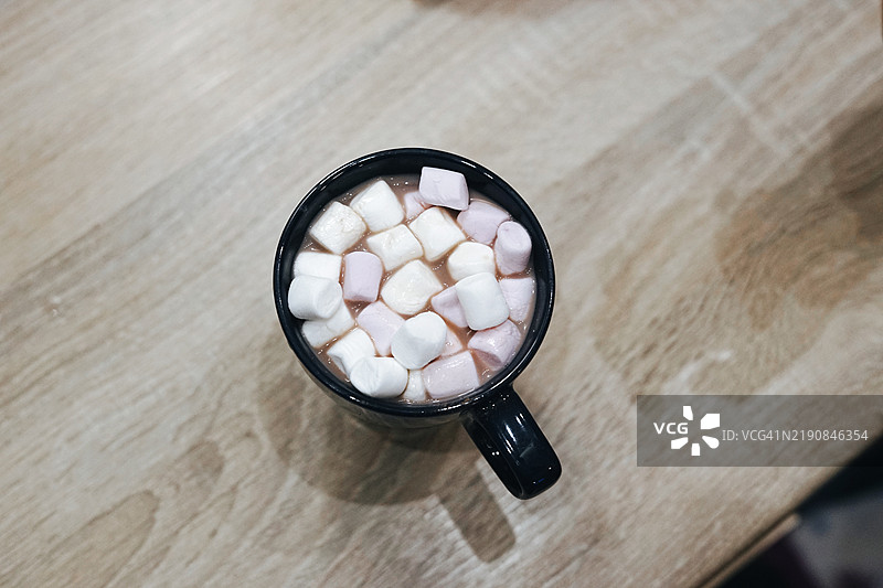 蓝色杯子装热巧克力，顶部放有粉色棉花糖，圣诞节假日美食，温暖饮品图片素材