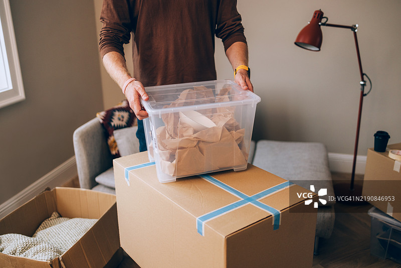 男子在纸箱中打包家庭物品，为搬家做准备图片素材