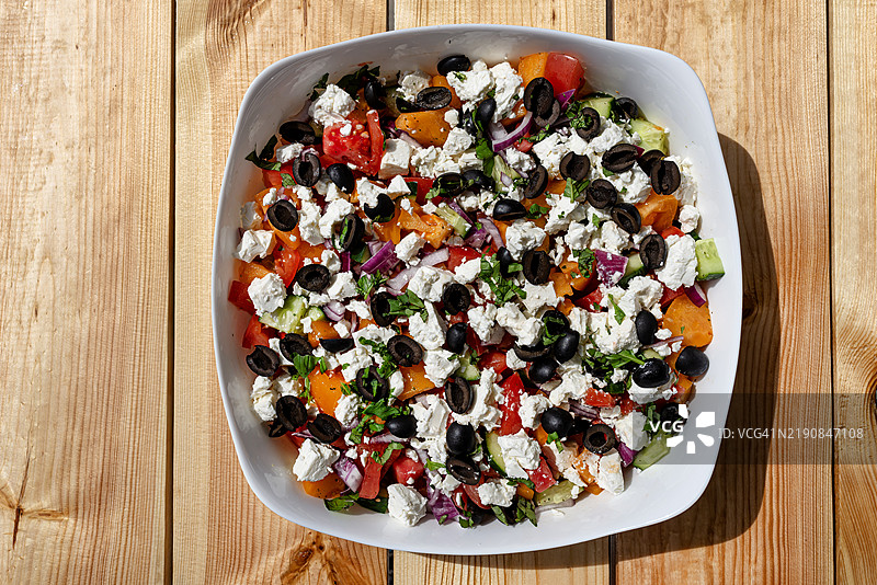 木桌上放着一盘配有羊奶酪和多种蔬菜的沙拉图片素材