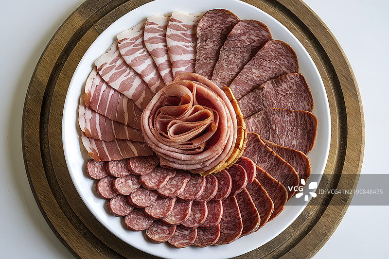 一只白色盘子里放着土耳其培根、熏牛肉和其他肉类切片图片素材