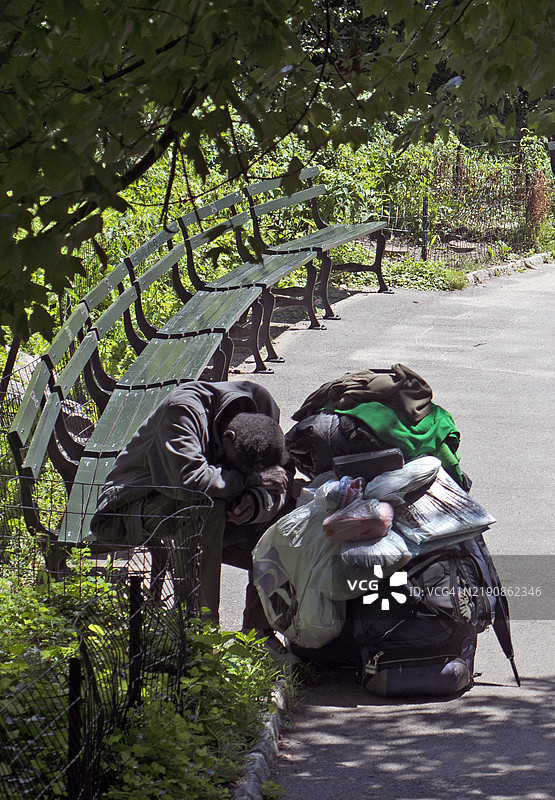 一名绝望的无家可归者坐在纽约中央公园的长椅上。图片素材