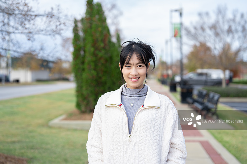 在美国哥伦布市，一位自信的亚洲女性在城市环境中站立，散发出美丽和现代优雅，体现出一种赋权的生活方式。图片素材