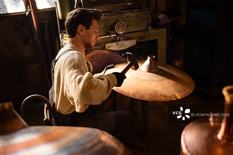 一个男人用锤子塑造铜器图片素材