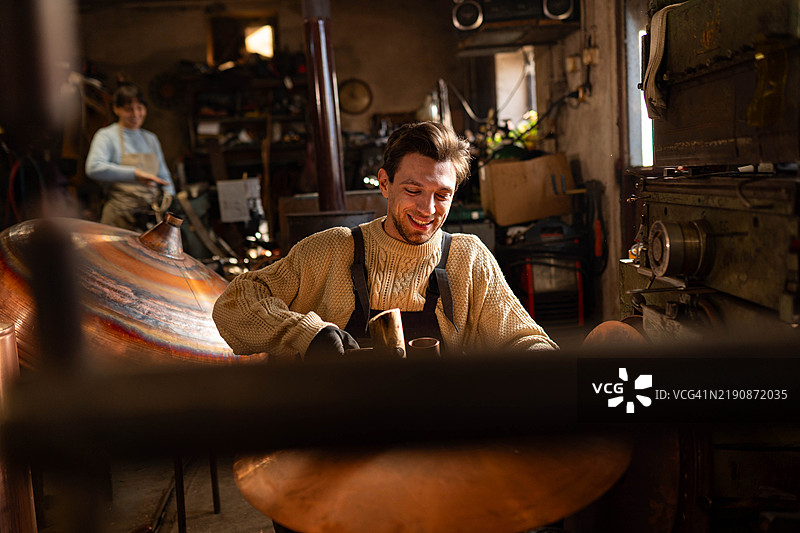 一个男人用锤子塑造铜材图片素材