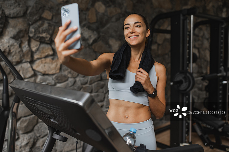 健身房里，苗条健康的女性用手机自拍图片素材
