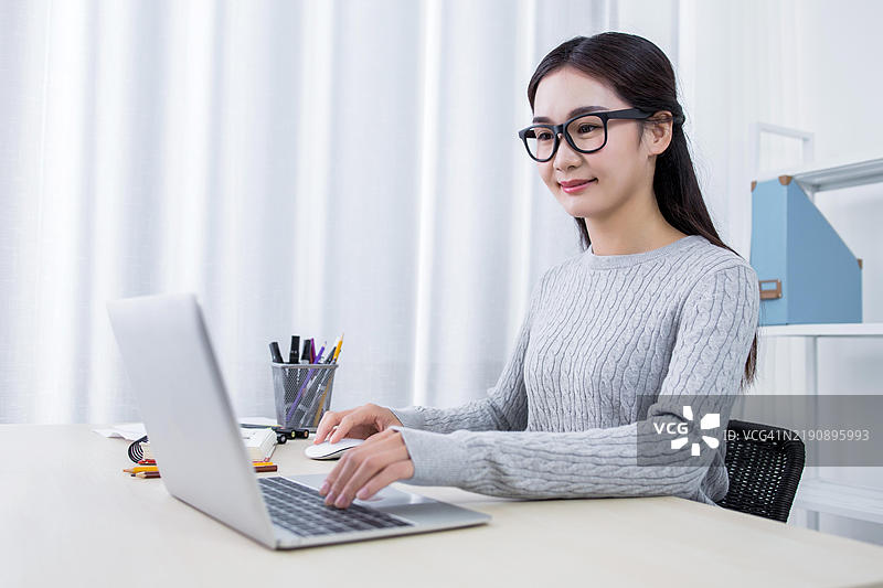 亚洲女性在家办公时使用笔记本电脑图片素材