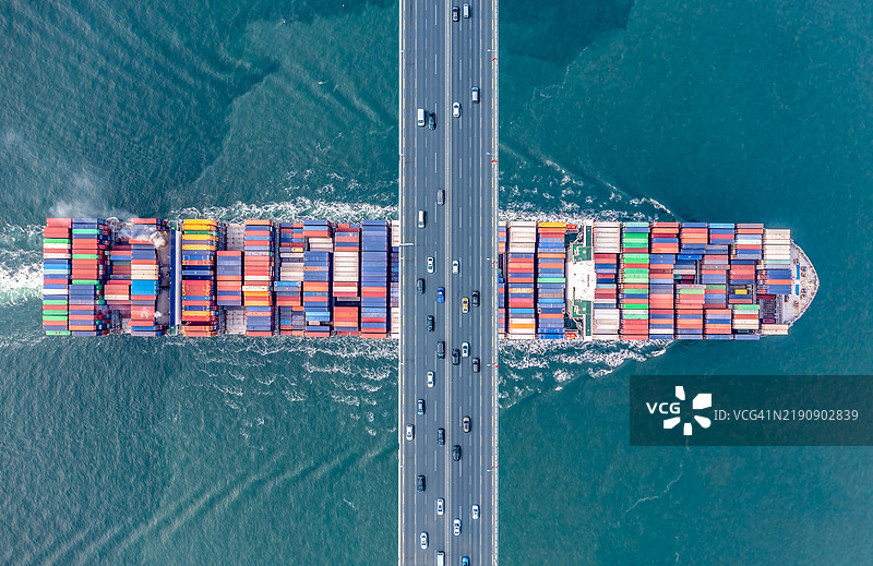 一艘满载集装箱的货船在现代桥下航行图片素材