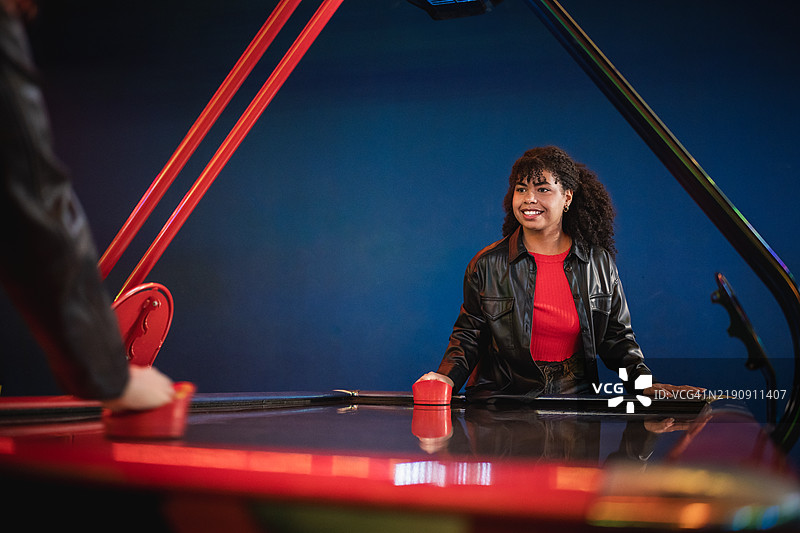 两个年轻人在游戏厅里玩空气曲棍球图片素材