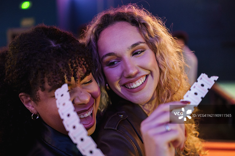 两位兴奋的年轻女性在游乐场手持票据图片素材