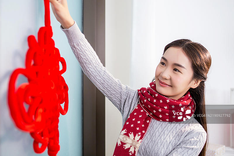 一位女性正在为春节挂上红色中国结装饰。图片素材