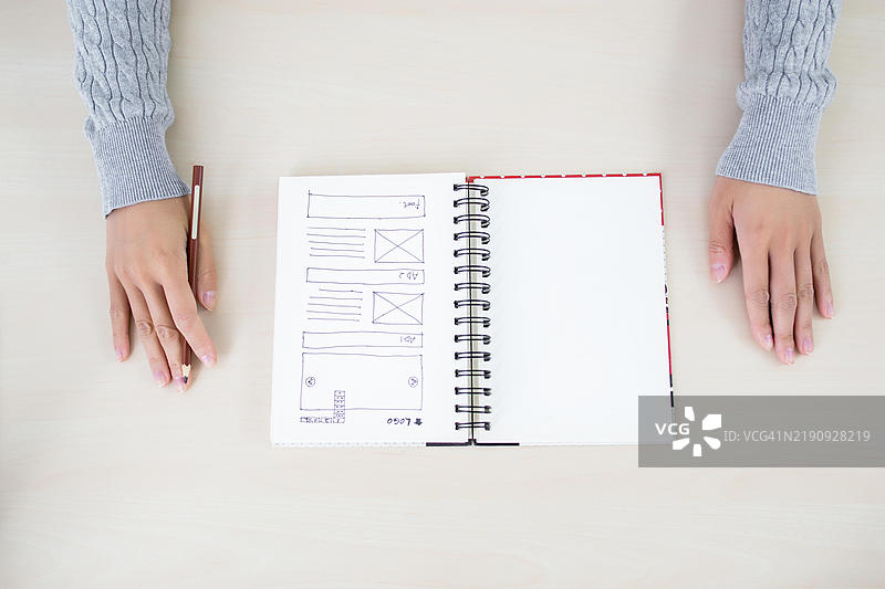 一个人在笔记本上勾勒网站布局图片素材