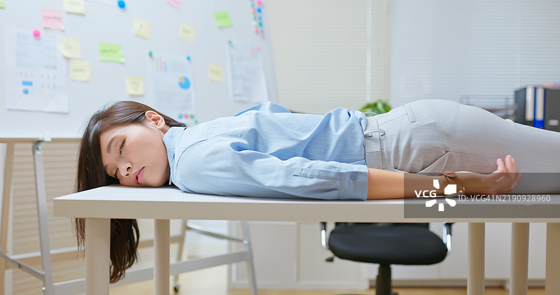 亚洲女商人平躺在桌子上图片素材