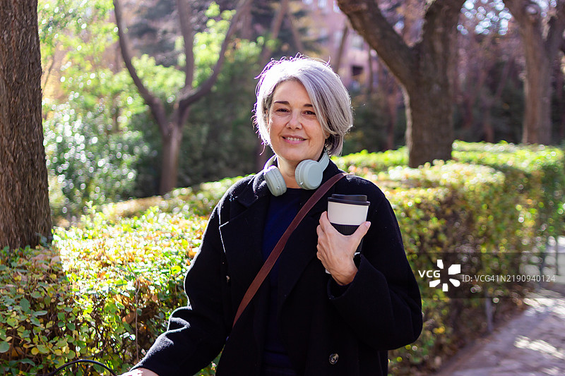 微笑的老年女性在公园享受咖啡休息时间图片素材