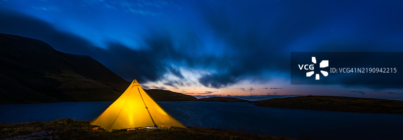 黄帐篷在湖边的山上野营，黄昏全景图片素材