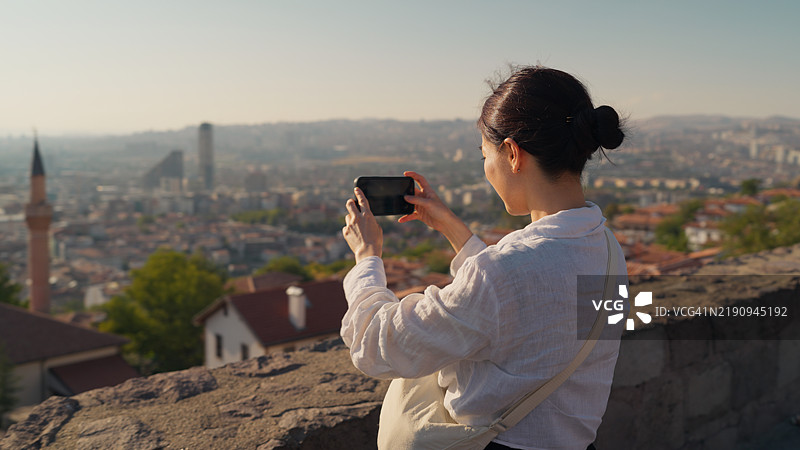 游客用智能手机拍摄土耳其安卡拉的城市风景图片素材
