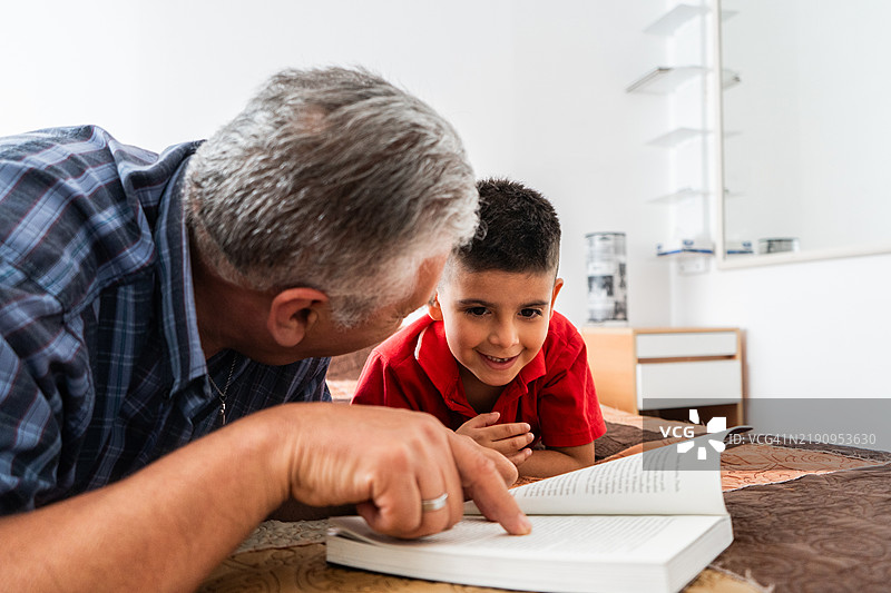 祖父在家中床上与孙子们一起阅读书籍图片素材