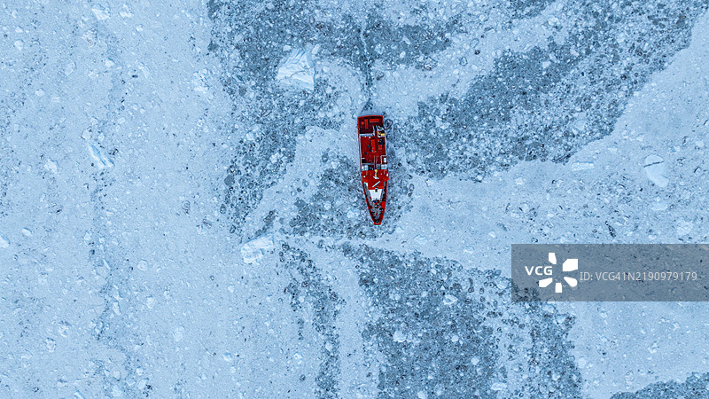 在格林兰西部的Eqi冰川下方，一艘小船漂浮在冰块之间的航拍图图片素材