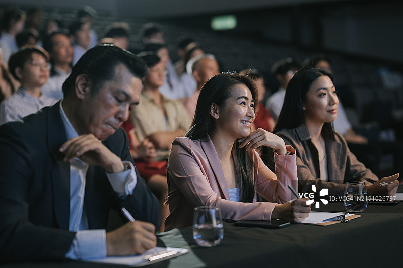 满意的快乐亚洲评委在观众面前为舞台表演比赛打分图片素材