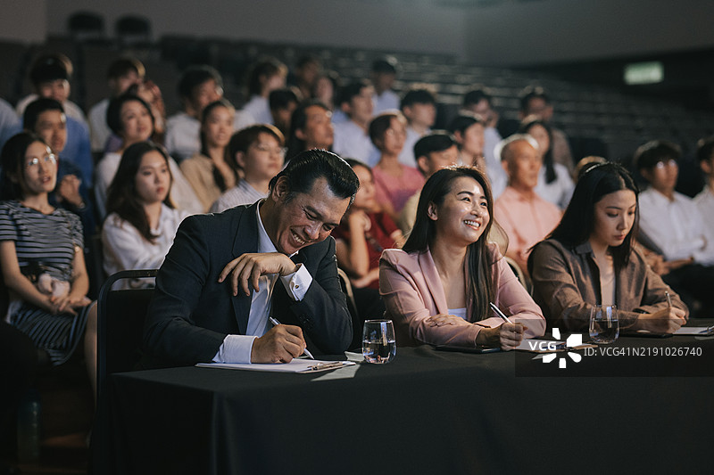 满意的快乐亚洲评委在观众面前为舞台表演比赛打分图片素材