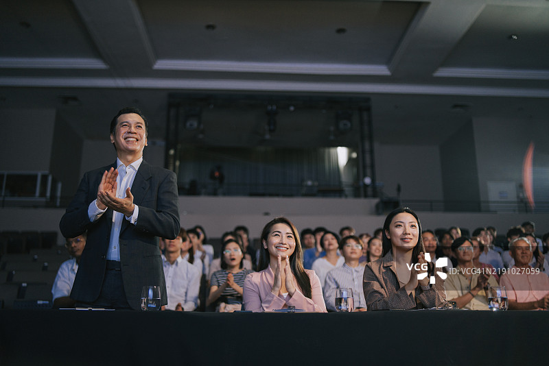 亚洲评委站起来为舞台表演比赛鼓掌，面向观众。图片素材