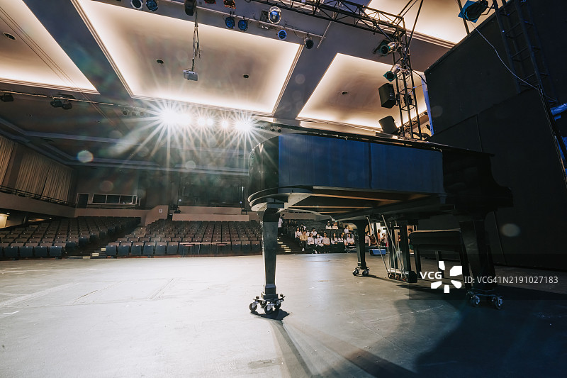 舞台上的大钢琴与坐在剧院观众席上的合唱比赛选手图片素材
