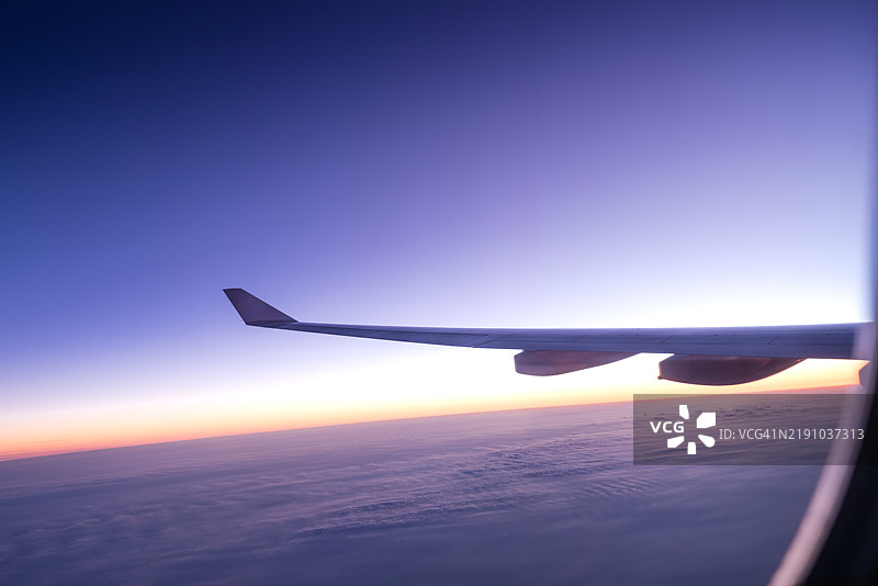 飞机在日落时飞过云层。图片素材