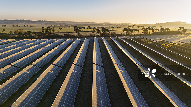 冬季寒霜清晨，俯瞰一片广阔的太阳能电池板阵列的无人机视角图片素材