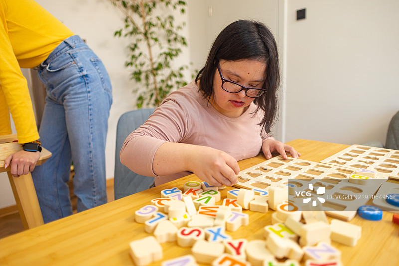 年轻女性与唐氏综合症正在用字母积木锻炼技能图片素材