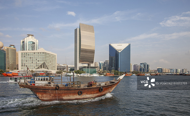 迪拜。传统阿拉伯船（达豪）与迪拜溪上的未来建筑。图片素材