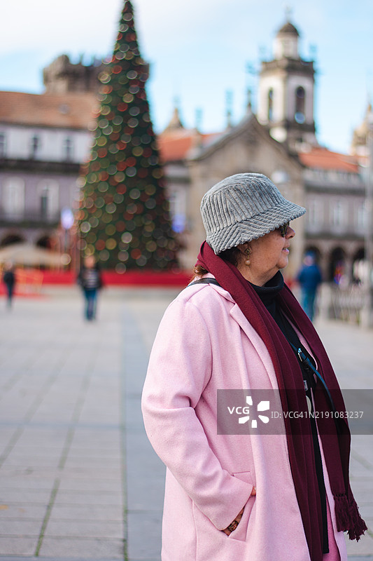 街头一位老年女性的肖像，背后有一棵圣诞树图片素材