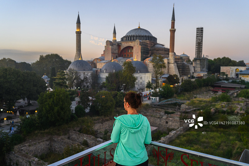女人在黄昏时分望向苏莱曼尼耶清真寺和城市天际线图片素材