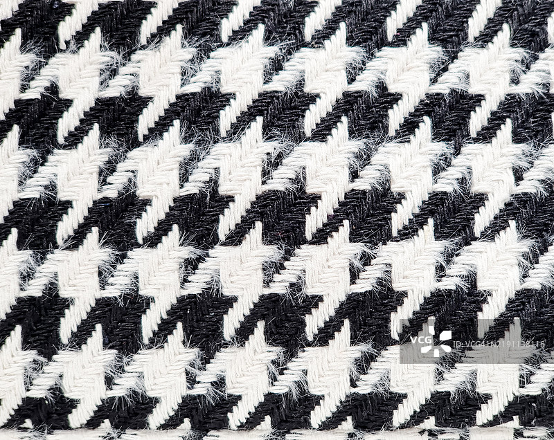 黑白照片，特写拍摄了一种装饰有著名小鸡爪纹理的面料，因为其原始质感让人联想到乌鸦的脚。照片拍摄于2024年12月意大利安科纳的室内。图片素材