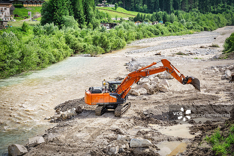 一台挖掘机在意大利圣斯特法诺·迪·卡多雷的皮亚韦河上修复河岸，照片拍摄于户外，时间为2024年6月。图片素材