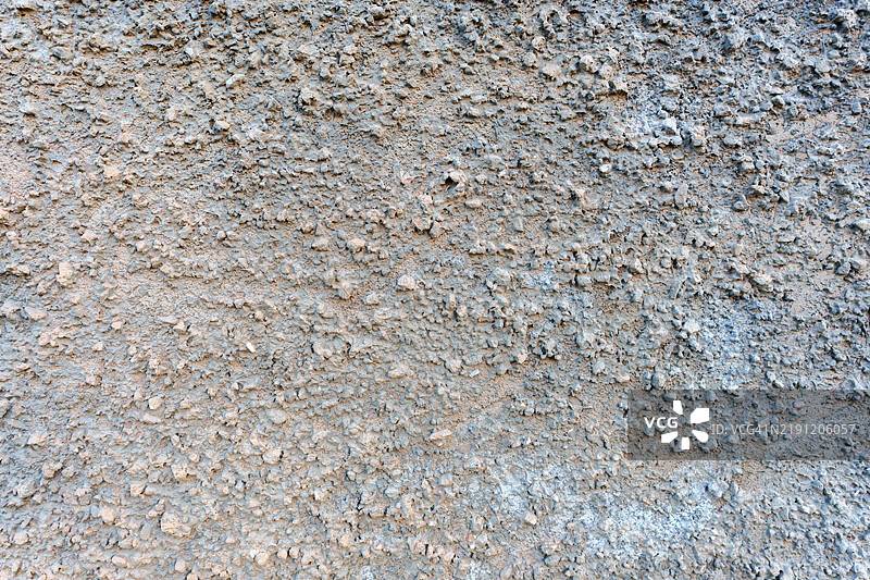 粗糙的混凝土表面突出嵌入的卵石，展现自然粗犷的纹理图片素材
