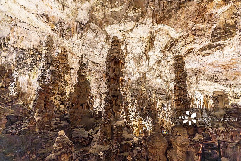 游客们在斯洛文尼亚著名的自然奇观——波斯托伊纳洞穴内惊叹于壮丽的钟乳石和石笋 formations。图片素材