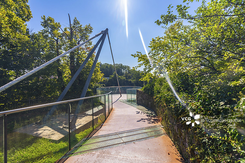 斯洛文尼亚克兰的现代人行天桥在郁郁葱葱的绿树中展现出创新设计与自然的连接。图片素材