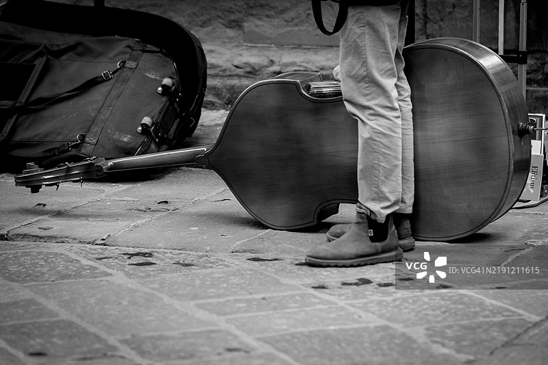 大街上的街头艺术家，腿间放着大提琴。图片素材