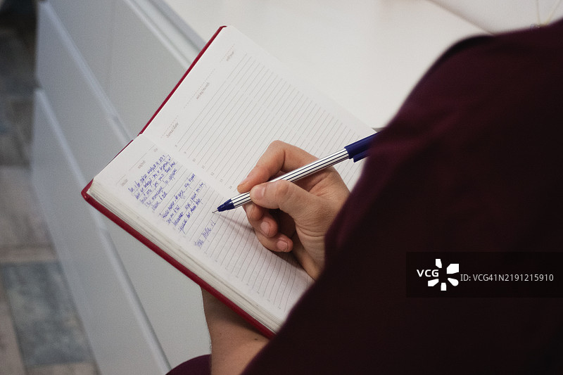 一个男人在笔记本上写字的手图片素材
