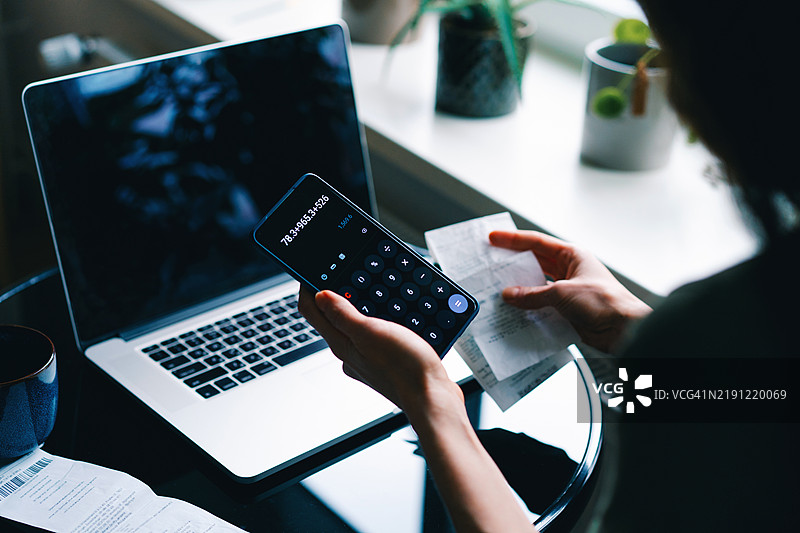 女性在家中使用智能手机和笔记本电脑计算财务图片素材