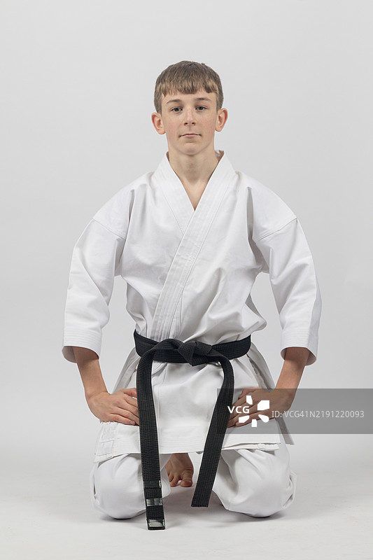 一名十五岁的少年，身穿黑带空手道服，背景为白色摄影棚。图片素材