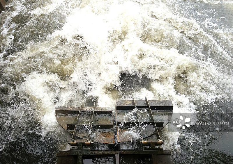 从上方俯视一个水闸或大坝，水流湍急而强劲。图片素材