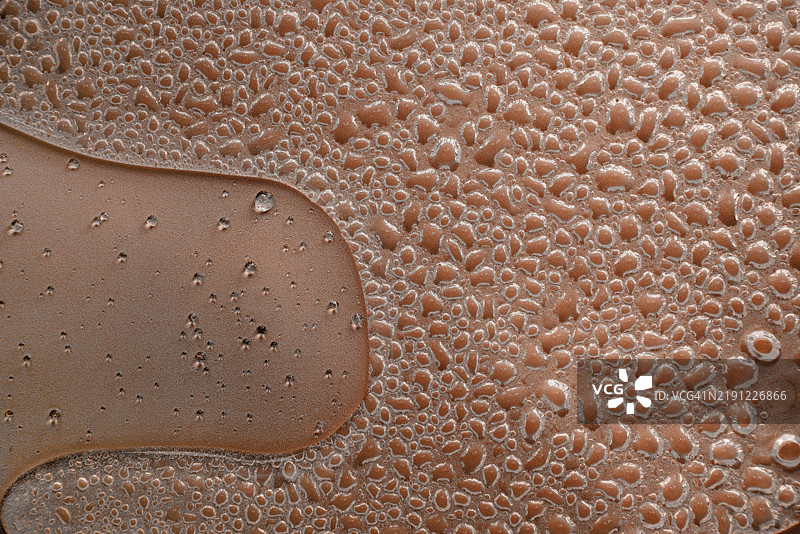 水滴在棕色表面上形成纹理图案图片素材