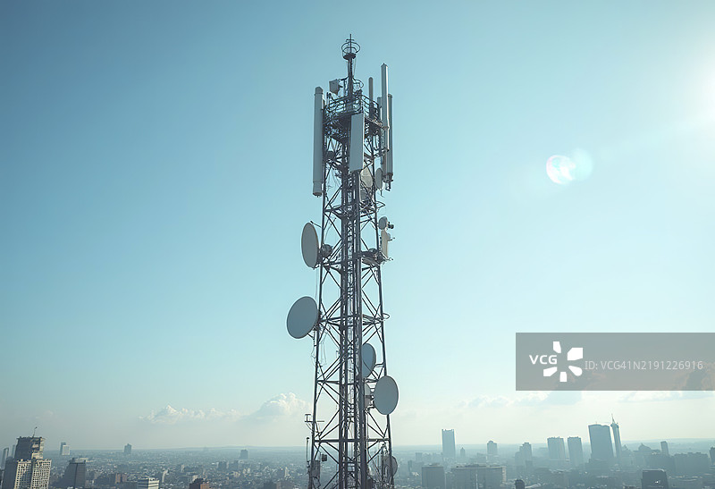 一座高大的通信塔，上面装有多个天线和碟形天线，背景是晴朗的蓝天图片素材
