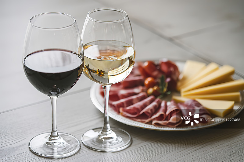 两杯红酒和白酒，配有一盘肉类和奶酪开胃菜图片素材