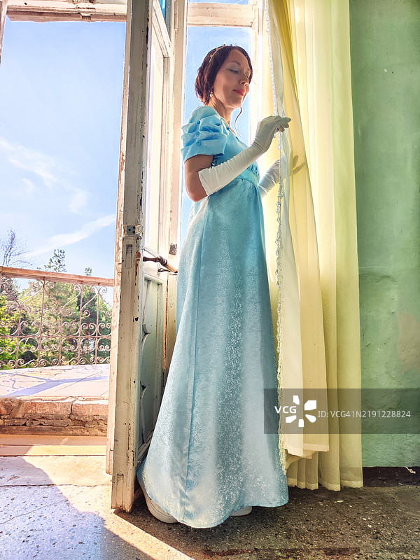 一位浪漫的公主在古老的城堡中，凝视着窗外。图片素材