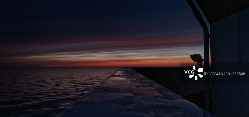 日落时分，站在栏杆旁的男人剪影与天空相映成趣图片素材