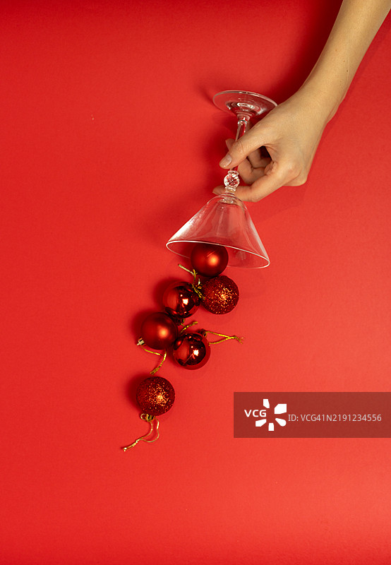 女性手握着一杯马提尼酒，旁边有圣诞球。图片素材